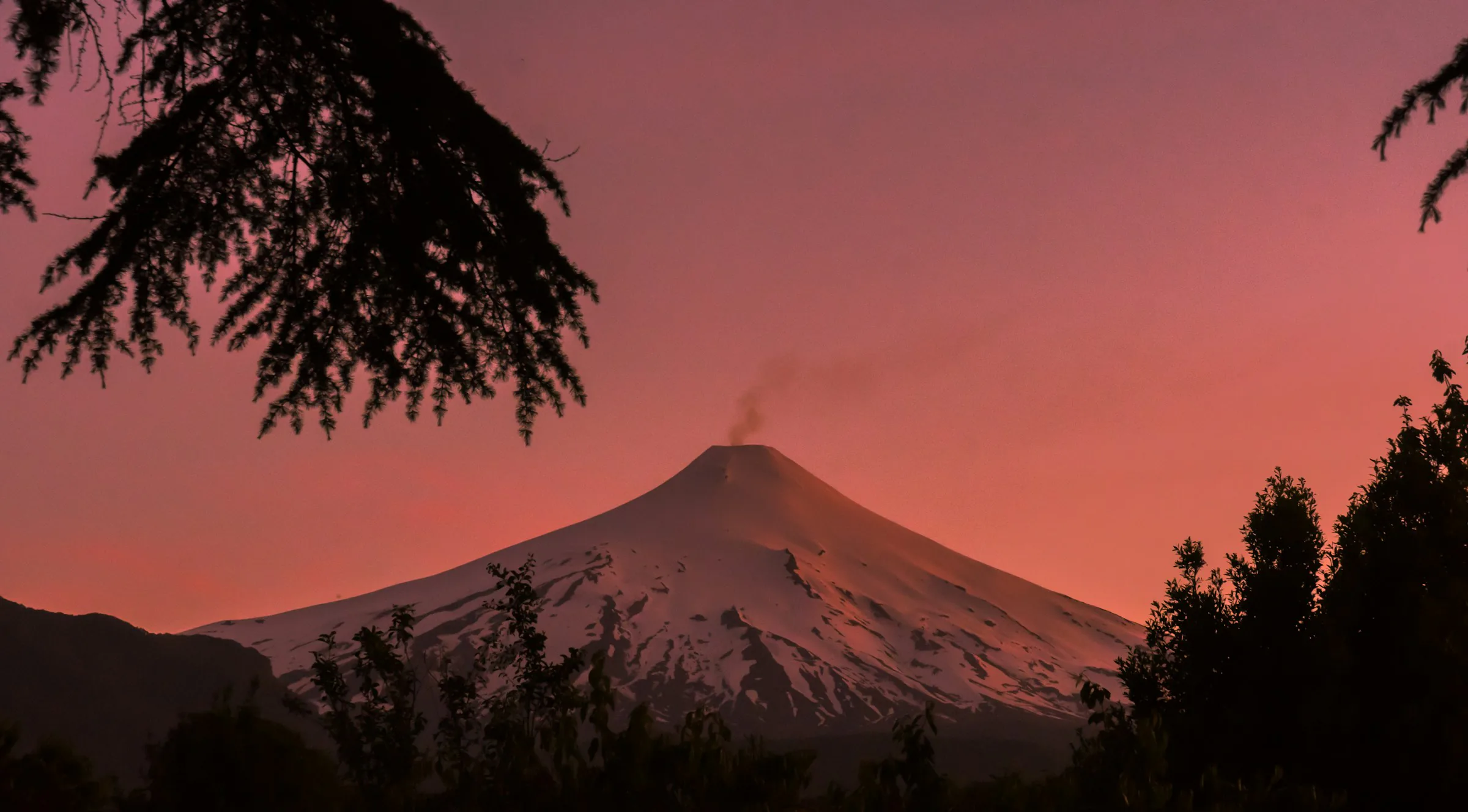 Schneebedeckter Vulkan Villarrica im intensiv roten Abendlicht über Pucón